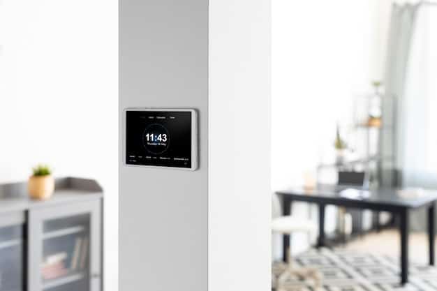A close-up shot of a smart thermostat mounted on a wall in a US home, displaying a user-friendly interface with temperature settings and energy usage data. The background shows a blurred living room setting, indicating the thermostat's integration into the home environment and its role in managing energy consumption.