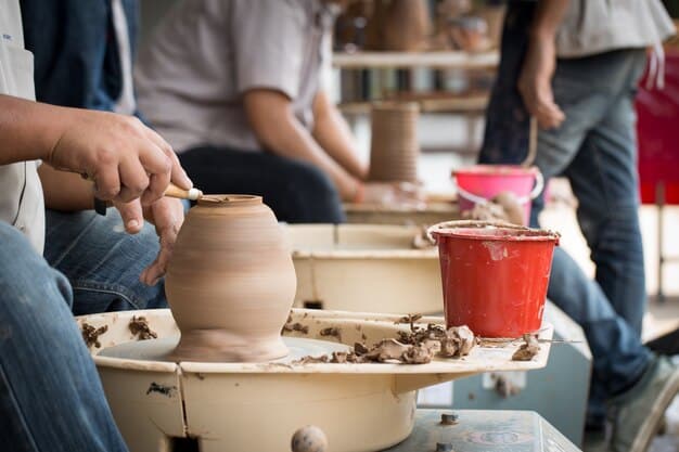 A wide-angle shot of tourists participating in a hands-on pottery workshop in Santa Fe, New Mexico. The tourists, of various ages and backgrounds, are actively engaged in creating their pottery pieces, guided by a local artisan. The workshop setting is authentic and rustic, with traditional tools and materials visible.